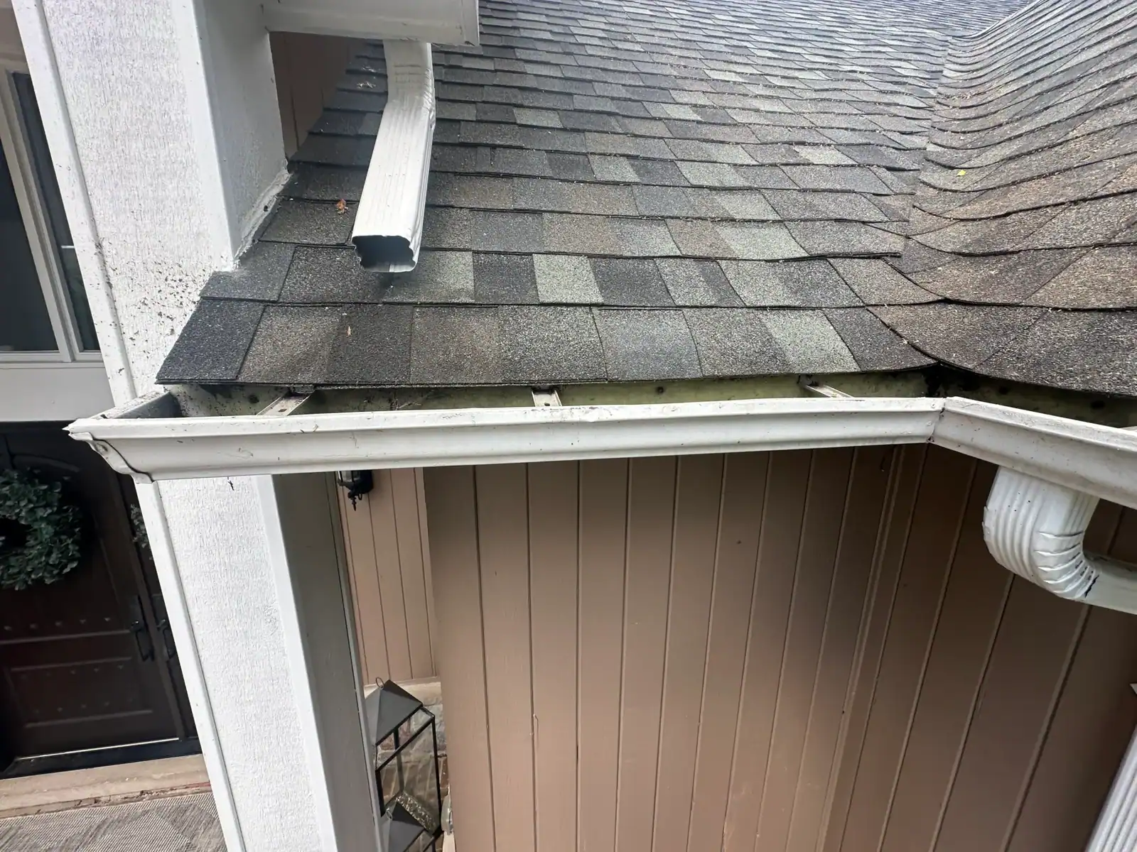 Damaged gutter beneath a shingled roof is visible, with signs of nearby recent tree removal in Oakland.